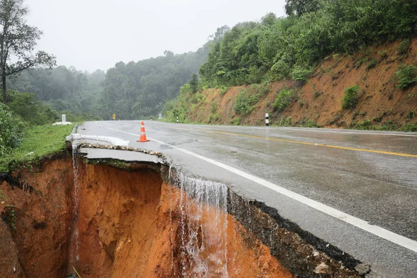 Şiddetli yağmurların yol açtığı heyelan, bozuk yol asfaltına neden olur. Sokakta yıkılmış çimento. Toprak kaymasından çıkan çatlak yol sağanak yağış yüzünden mahvoldu.