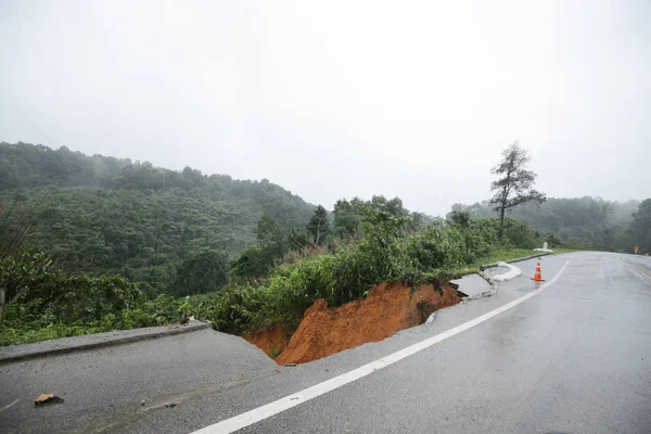 Şiddetli yağmurların yol açtığı heyelan, bozuk yol asfaltına neden olur. Sokakta yıkılmış çimento. Toprak kaymasından çıkan çatlak yol sağanak yağış yüzünden mahvoldu.