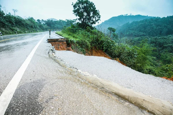 Şiddetli yağmurların yol açtığı heyelan, bozuk yol asfaltına neden olur. Sokakta yıkılmış çimento. Toprak kaymasından çıkan çatlak yol sağanak yağış yüzünden mahvoldu.