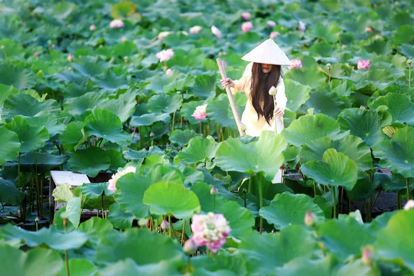 Ahşap antik tekne ile lotus gölet ao dai traditonal vietnamlı sarı ve beyaz elbise Vietnamlı kadın.