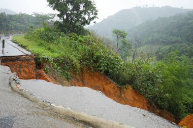 Şiddetli yağmurların yol açtığı heyelan, bozuk yol asfaltına neden olur. Sokakta yıkılmış çimento. Toprak kaymasından çıkan çatlak yol sağanak yağış yüzünden mahvoldu.
