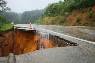 Şiddetli yağmurların yol açtığı heyelan, bozuk yol asfaltına neden olur. Sokakta yıkılmış çimento. Toprak kaymasından çıkan çatlak yol sağanak yağış yüzünden mahvoldu.