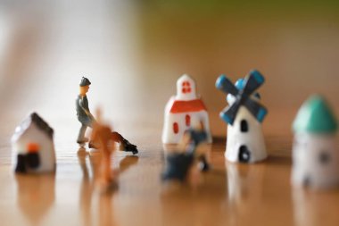 Küçük bir ev, küçük bir yel değirmeni, minyatür bir şehir kadar küçük bir kule ahşap zemindeki kötü oyuncaklar gibi işçilerle birlikte çalışma ve yaşama kavramında.