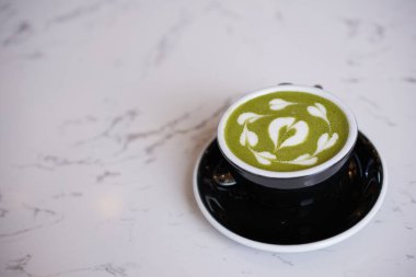 Yeşil çay latte sanatı, siyah fincanda beyaz kremalı Matcha japon. Kahve dükkanında kalp sütlü çay içeceği.