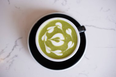 Yeşil çay latte sanatı, siyah fincanda beyaz kremalı Matcha japon. Kahve dükkanında kalp sütlü çay içeceği.