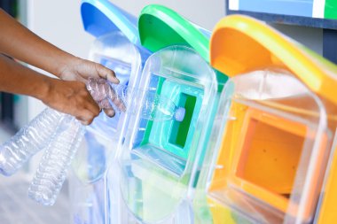 Yeşil Dünya 'nın korunması için çevre ve geri dönüşüm fikri olarak boş plastik şişeyi yeşil çöp kutusuna koyan bir adam..