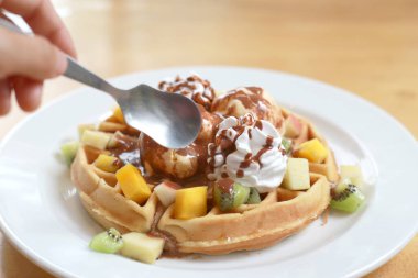 Dondurmalı çikolatalı waffle ve çırpılmış krema ve üstten küçük kavanozlarla sulanan çikolatalı top domuz. Beyaz tabakta tatlı soğuk Avrupa tatlısı.