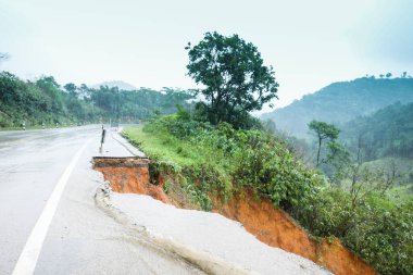 Şiddetli yağmurların yol açtığı heyelan, bozuk yol asfaltına neden olur. Sokakta yıkılmış çimento. Toprak kaymasından çıkan çatlak yol sağanak yağış yüzünden mahvoldu.