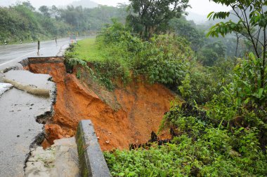 Şiddetli yağmurların yol açtığı heyelan, bozuk yol asfaltına neden olur. Sokakta yıkılmış çimento. Toprak kaymasından çıkan çatlak yol sağanak yağış yüzünden mahvoldu.