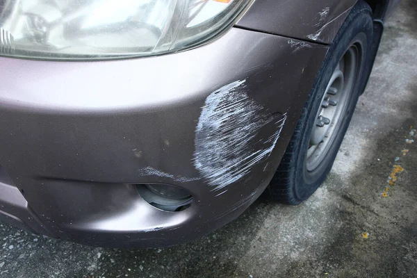 Altın rengi kahverengi arabanın ön lambası kırılmış. Çarpışan araba parçalanmış. Araba kazası sigortası önemlidir.