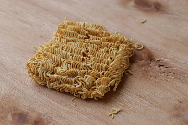 Crispy and dry instant square noodles. Uncooked and unhealthy dried noodles on wood pallet.