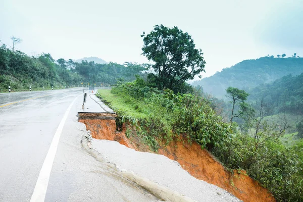 Şiddetli yağmurların yol açtığı heyelan, bozuk yol asfaltına neden olur. Sokakta yıkılmış çimento. Toprak kaymasından çıkan çatlak yol sağanak yağış yüzünden mahvoldu.