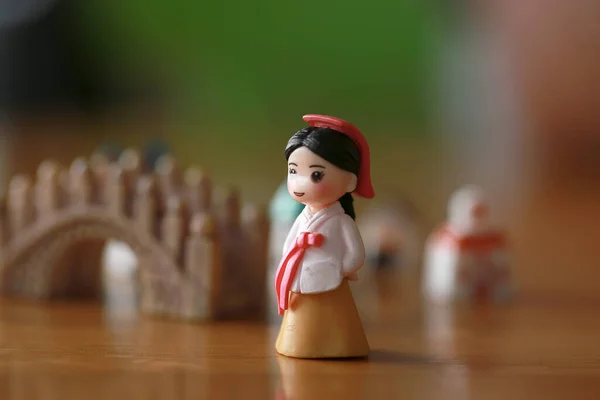 Korean woman doll in traditional costume as hanbok standing in front of rock bridge. Miniature of doll for traditional travel Korean place concept.