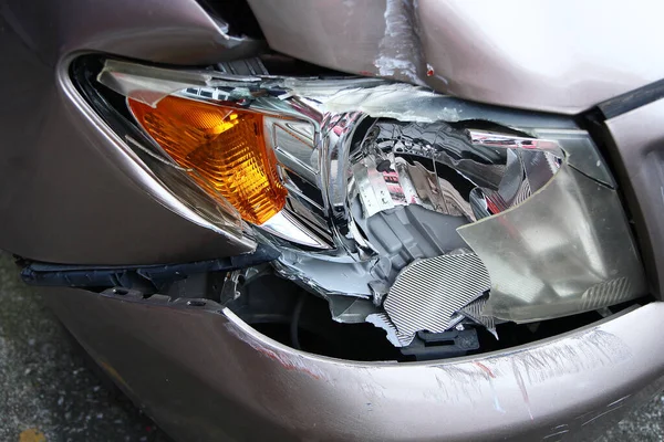 Golden brown car\'s front light is broken. Crashed car destroyed automobile part. Insurance of car crash is important