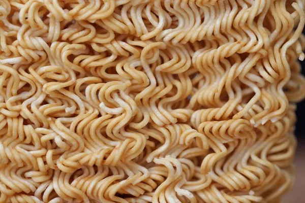 Crispy and dry instant square noodles. Uncooked and unhealthy dried noodles on wood pallet.