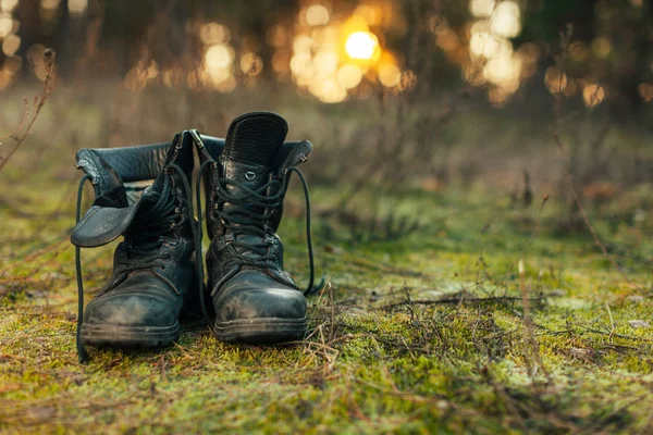 Close up of vintage pair of walking boots on boulder grassland background. Hard travel concept