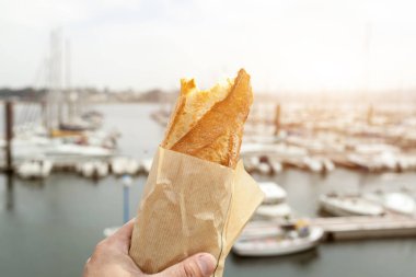 Kavramsal natürmort sanat fotoğraf deniz ve yat arka plan kağıda sarılı bir baget ekmek. Uzay kopyalayın. Reklam, yemek, ekmek ve ticari tasarım