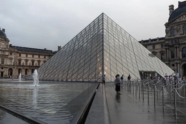Paris, Fransa. 01 Haziran 2018: Louvre Müzesi yaz günbatımı ile kare. Eski Rönesans bina güneş tarafından aydınlanmış ve Cam Piramit ortada duruyor