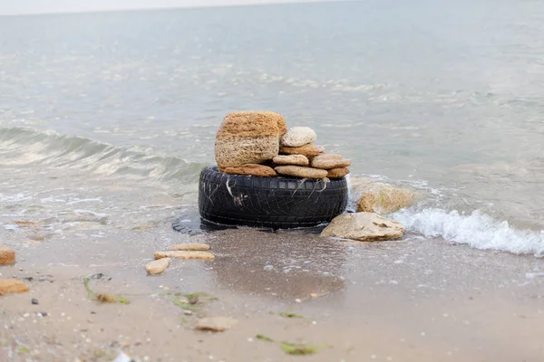 Vecchio pneumatico di gomma nera lasciato su una spiaggia, concetto di inquinamento ambientale, attenzione selettiva — Foto Stock
