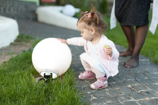Klein meisje kind spelen op het grasveld in de achtertuin met een grote elektrische lamp. — Stockfoto
