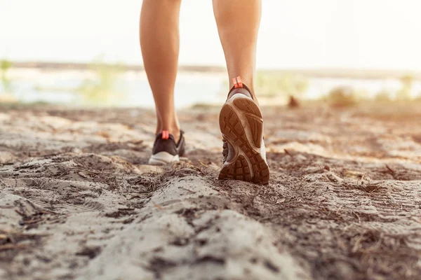 Close up of the legs of a young woman who is running off road in a park — Stock Photo, Image