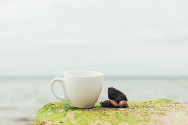 White mug, mock up, empty space for artwork, text, standing on wood plank, turquoise sea, clear blue sky, horizon, sunlight, nature