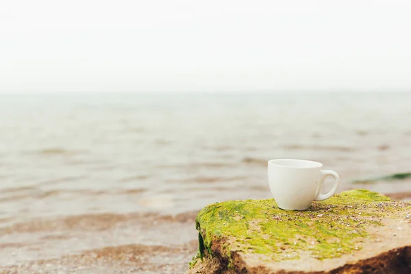 White mug, mock up, empty space for artwork, text, standing on wood plank, turquoise sea, clear blue sky, horizon, sunlight, nature