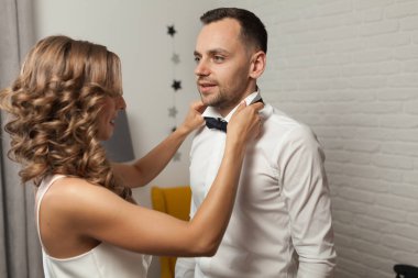 Gelin ve damat sabah otelden bir düğün gününde. Papyon damat için sabitleme bir yeni evli çift kadın yardım giyinme