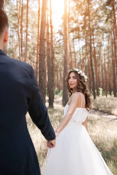 Folge mir meinem Liebeskonzept. attraktive junge Frau im weißen Hochzeitskleid hält Hand ihres Freundes und geht auf dem schönen Garten in eine glückliche Zukunft — Stockfoto