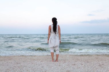 Plaj pastoral sahne zevk kafasına dreadlock ile beyaz elbiseli güzel kadının arkadan görünüm.