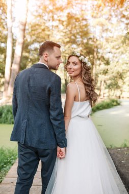 Gelin ve damat gün açık havada yaz doğa üzerinde yürüme düğününde. Gelin Çift, mutlu yeni evli kadın ve yeşil park kucaklayan adam. Sevgi dolu evlilik çift açık. Gelin ve damat