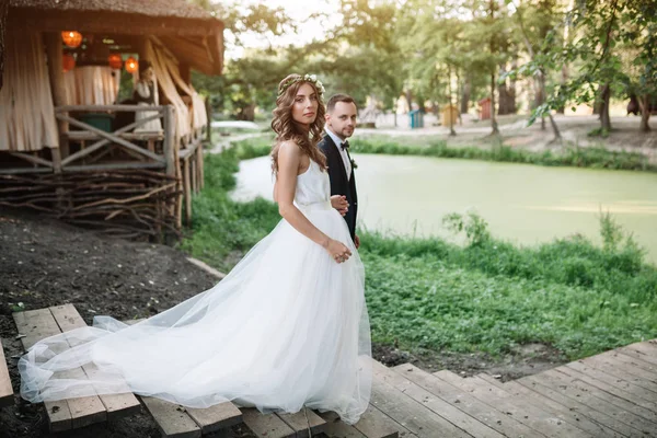 Noiva e noivo no dia do casamento andando ao ar livre na natureza de verão. Casal nupcial, mulher recém-casada feliz e homem abraçando no parque verde. Casal de amor ao ar livre. Noiva e noivo — Fotografia de Stock