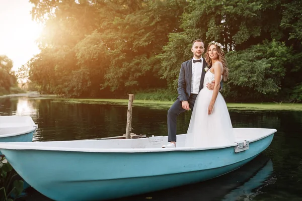 Schönes Paar Bräutigam und Braut in der Nähe Fluss Boot. vor dem Hintergrund der wunderschönen Natur und des Sonnenuntergangs — Stockfoto