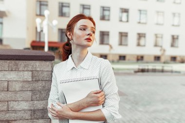 Dizüstü ev ödevi ve mutlu gülümseyerek ile sarılma çilli güzel kırmızı saçlı kız. Geri okul kavramı. Bir öğrenci portresi