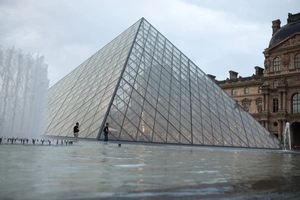 París, Francia. 01 de junio de 2018: Plaza del Museo del Louvre durante una puesta de sol de verano. El viejo edificio renacentista está iluminado por el sol y la pirámide de vidrio está en el medio. . — Foto de Stock