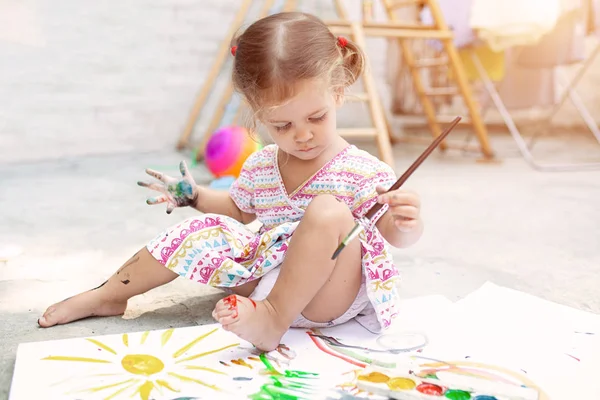 Nettes kleines kaukasisches Mädchen, das es genießt, im Hinterhof mit Papier, Aquarell und Pinsel zu malen. Selektiver Fokus — Stockfoto