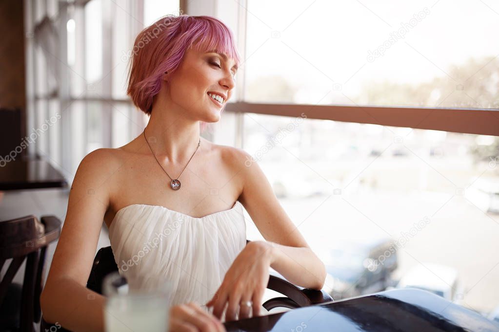Smiling woman is sitting in comfortable cafe-bar during her recreation time, cheerful happy female rests after work waits her friends in cozy coffee shop