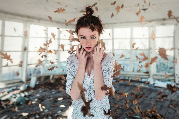 Chica de pelo rojo con pecas de pie en las hojas de otoño que caen. Concepto de otoño — Foto de Stock