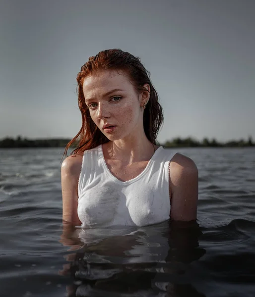Junge traurige hübsche rothaarige Frau, die im Wasser steht — Stockfoto