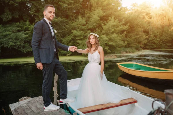 Casal bonito noivo e noiva perto do barco do rio. Contra o pano de fundo da bela natureza e pôr do sol — Fotografia de Stock