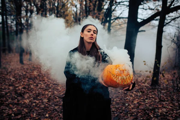 Mladá žena držící halloween dýně s bílý kouř, vznikající uvnitř — Stock fotografie