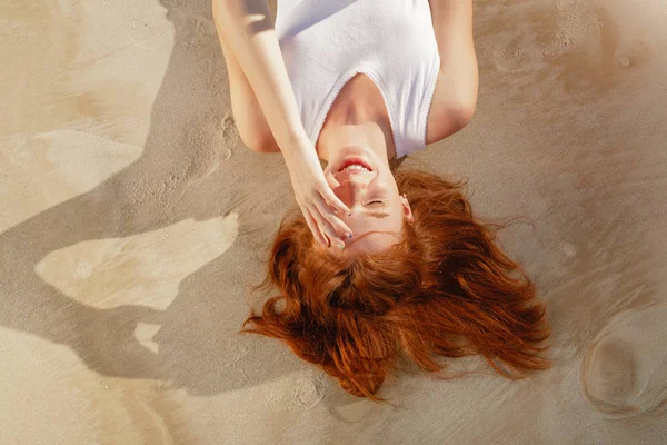 Giovane bella donna dai capelli rossi sdraiata sulla spiaggia — Foto Stock