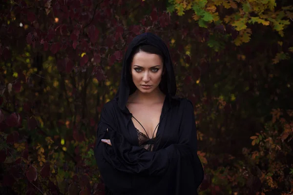 Jonge vrouw in de zwarte mantel in de herfst bos — Stockfoto