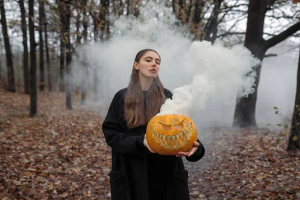 Mladá žena držící halloween dýně s bílý kouř, vznikající uvnitř — Stock fotografie