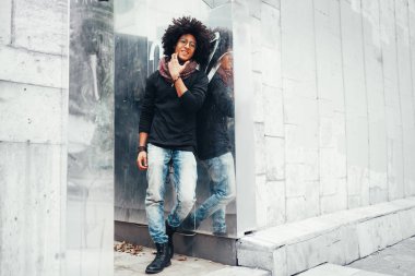 Genç güzel moda Afrika kökenli Amerikalı beyaz duvara yakın duruyor