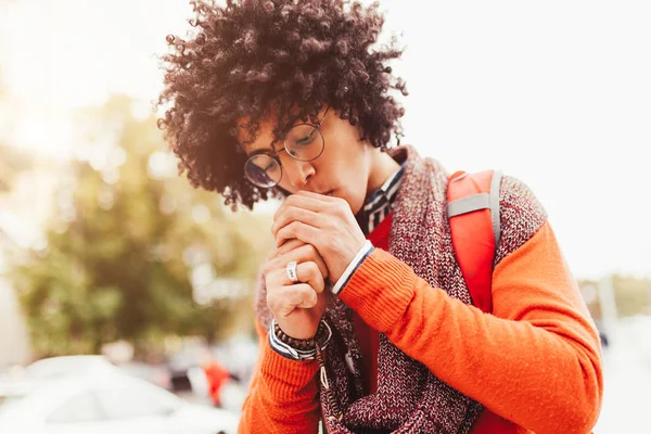 Jonge modieus gekleed gekrulde zwarte Afrikaanse Amerikaan met glazen wandelingen door de straten tegen een wolkenkrabber. — Stockfoto