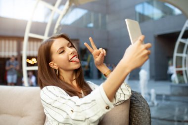 Çizgili şık elbise giymiş bir güzel kız bir yaz açık kafede oturuyor ve emrine ve arkadaşları ya sevgilisi için bekliyor. Telefonda bir ileti yazdırır