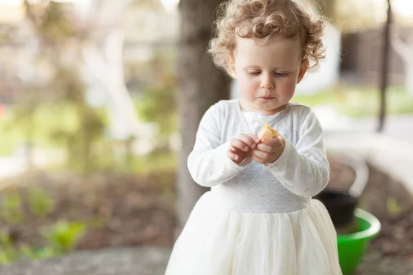 Mooi meisje kijkend naar haar snack in de straat — Stockfoto