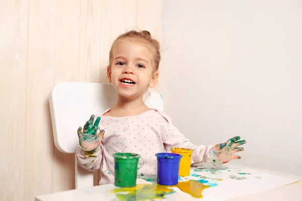 Mooi meisje tekent met de vinger de verf op een wit vel papier. De ontwikkeling van het creatieve kind in de kleuterschool of vrije tijd thuis — Stockfoto