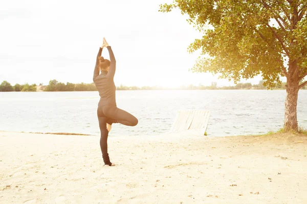Γυμναστήριο, Αθλητισμός, άνθρωποι και lifestyle έννοια - νεαρή γυναίκα, κάνοντας ασκήσεις γιόγκα στην παραλία από πίσω — Φωτογραφία Αρχείου